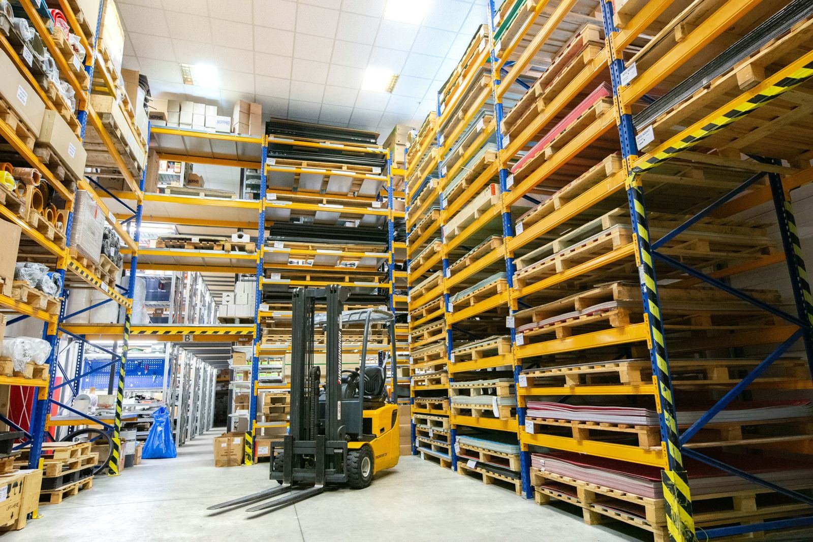 Forklift in a tall racked warehouse aisle