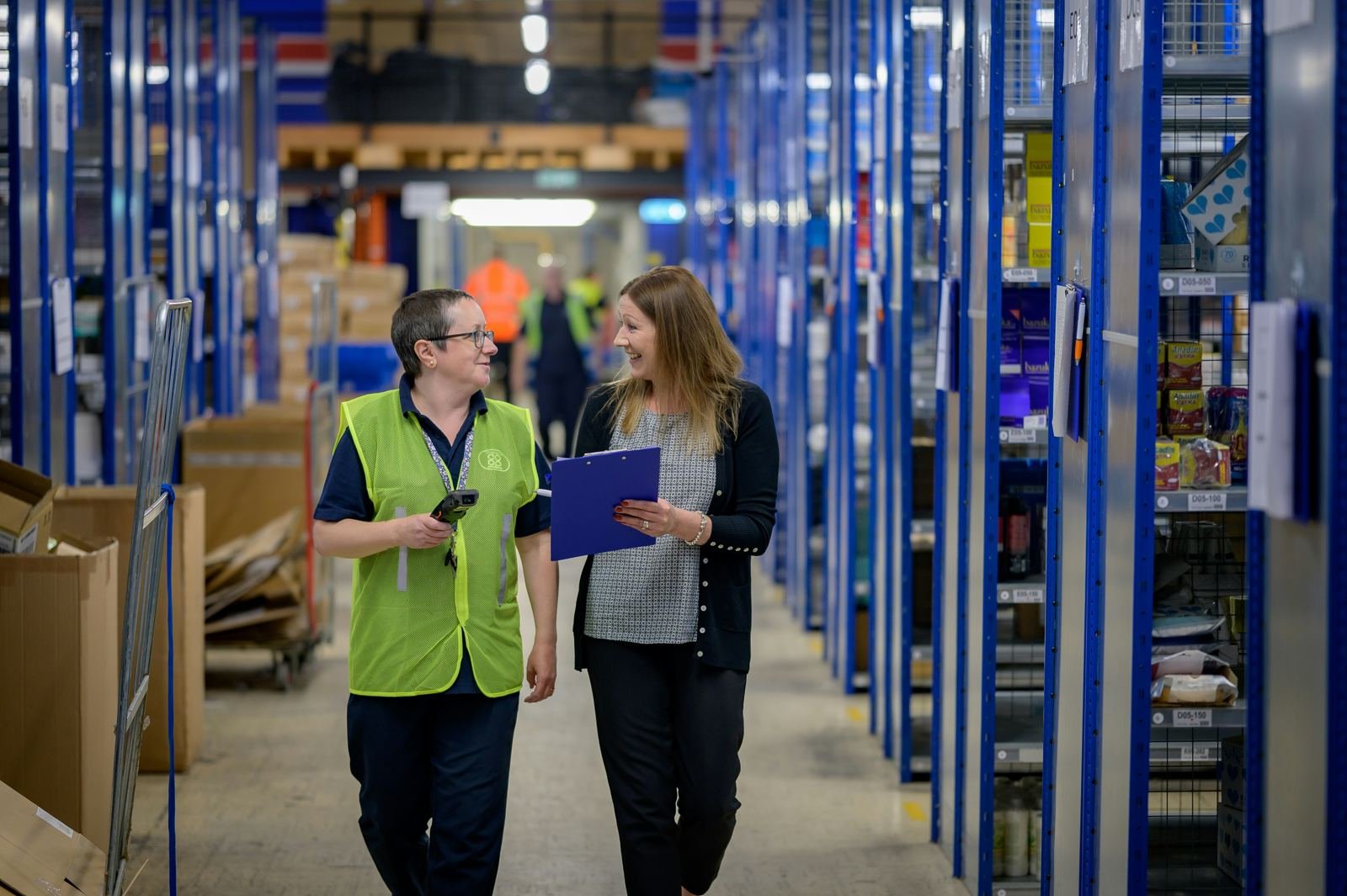 Warehouse manager and colleague reviewing stock in a racking aisle